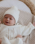 Smiling Newborn baby in bassinet lying on Haze cotton knit blanket
