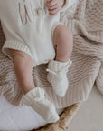 Baby wearing socks lying in crib on Haze cotton knit blanket