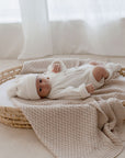Newborn baby in bassinet lying on Haze cotton knit blanket