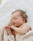 Sleeping baby in crib wrapped in Haze cotton knit blanket