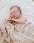 Sleeping baby in crib wrapped in Haze cotton knit blanket