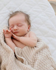 Baby in crib wrapped in Haze cotton knit blanket