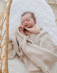 Sleeping baby in crib wrapped in Haze cotton knit blanket