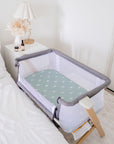 Wide View of Co Sleeper Cot Next to Bed with Sage Sunshine Waterproof Sheets