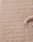 Close-up of a baby sitting on the nude Bambella play mat